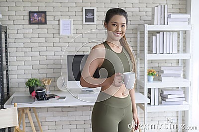 Young fitness woman in sportswear having a cup of coffee after exercising at home, Healthy and Lifestyles Stock Photo