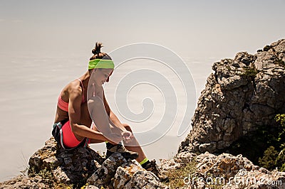 Young fitness woman trail runner tying shoelace at mountain top Stock Photo