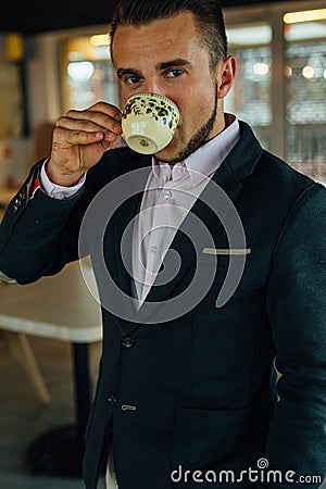 Young focused businessman drinking coffee in cafÃ©. Indoor photo Stock Photo