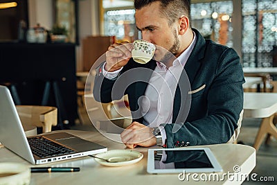 Young focused businessman sitting in cafÃ©, working on his lapto Stock Photo