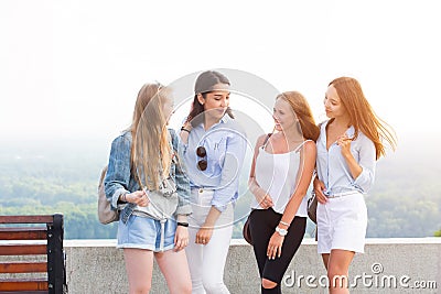 Young four student girls talking in the Park after College. Women smile, rejoice, have fun on the background Stock Photo