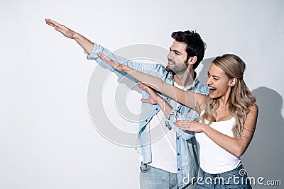 Young and free. Beautiful young couple gesturing and smiling while standing against grey background Stock Photo