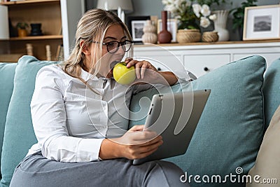 Young freelance business woman working at home on tablet as product strategy expert. Female expatriate remote work on internet on Stock Photo