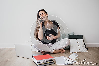 Mother working at home with baby in ergo backpack Stock Photo