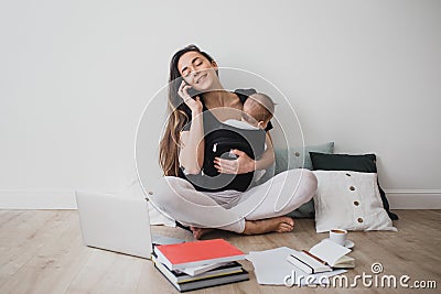 Mother working at home with baby in ergo backpack Stock Photo