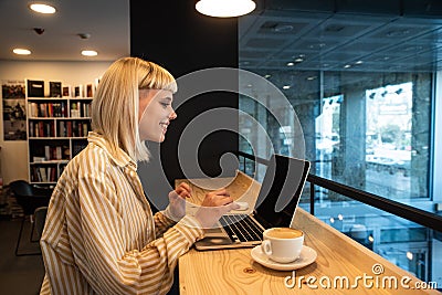 Young freelancer business woman or student, expat or vlogger preparing for work and internet online video call from bookstore or Stock Photo