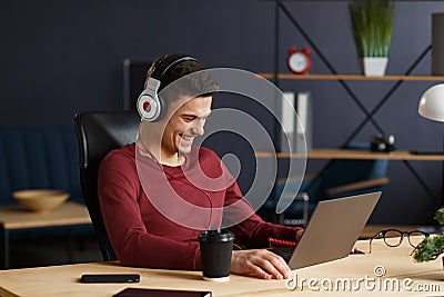 Young freelancer working in home office with laptop and listenin Stock Photo