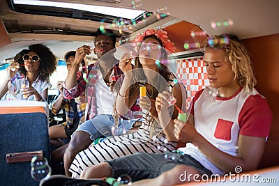 Young friends blowing bubble wands in camper van Stock Photo