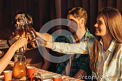 Young friends celebrate at sunset dinner, toast with drinks, happy people at terrace party eating barbecue Stock Photo