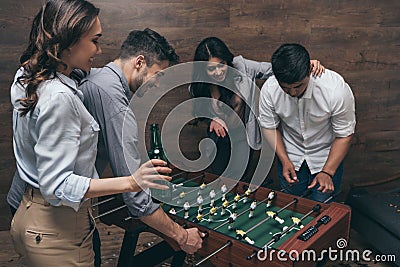 Young friends drinking beer and playing foosball indoors Stock Photo