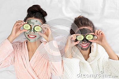 Young friends with facial masks having funon bed at pamper party, top view Stock Photo