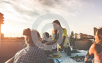 Young friends having barbecue party at sunset on terrace patio - Happy people doing bbq dinner outdoor eating and drinking wine - Stock Photo
