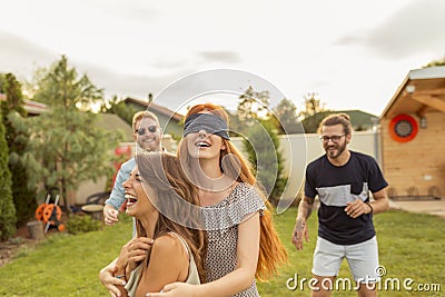 Young friends playing blind man`s buff in the backyard Stock Photo