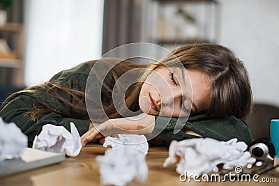 Young frustrated exhausted woman laid her head down on the table sitting at desk with pc laptop. Stock Photo