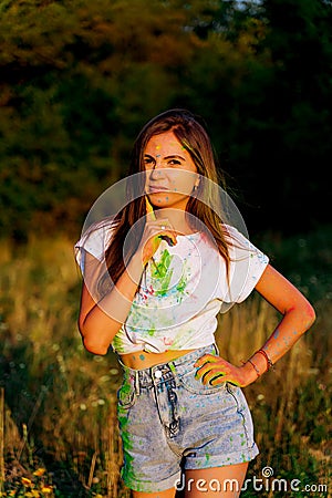 A young funny girl smeared with paint holds a finger to her head Stock Photo