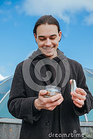 Young gay hipster eating peanuts at the street smiling happy sunglasses Stock Photo