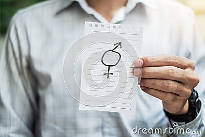 Young gay Man hand showing paper note with gender of LGBTQ symbol for Lesbian, Gay, Bisexual, Transgender and Queer community Stock Photo