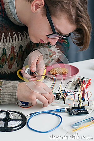 Young geek connecting wires to breadboard Stock Photo