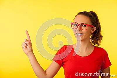 Young geek woman in red t shirt point in copy space over vibrant Stock Photo