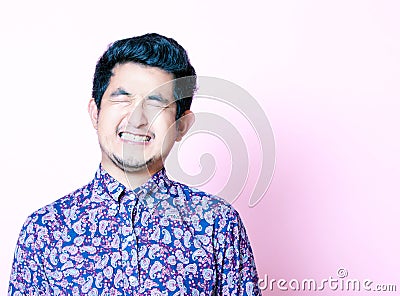 Young Geeky Asian Man in colorful shirt closing both eyes Stock Photo