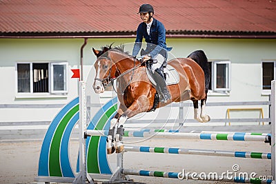 Young gelding horse and handsome man rider jumping obstacle Stock Photo