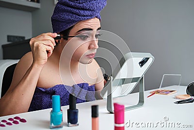 Young gender fluid person applying eye mascara. Stock Photo