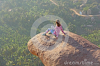 A young girl on a background of sunrise or sunset sits on top of Stock Photo