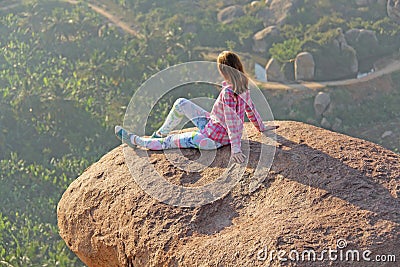 A young girl on a background of sunrise or sunset sits on top of Stock Photo