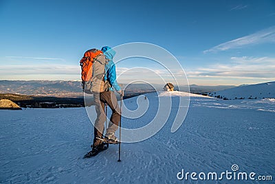 Girl backpacking towards Wolfsberger hut with snowshoes on a sunny day in winter in sunset, Saualpe alpine range, Austria Stock Photo