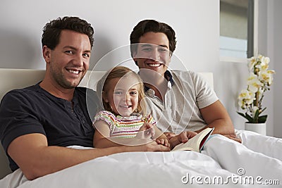 Young girl in bed with her male parents, looking to camera Stock Photo