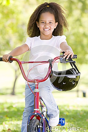 Young girl on bicycle outdoors smiling Stock Photo