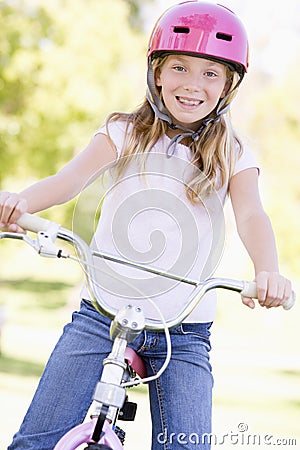 Young girl on bicycle outdoors smiling Stock Photo