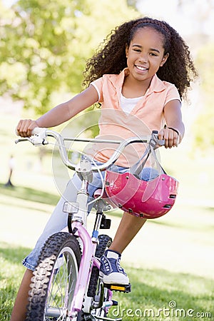 Young girl on bicycle outdoors smiling Stock Photo