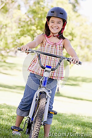 Young girl on bicycle outdoors smiling Stock Photo