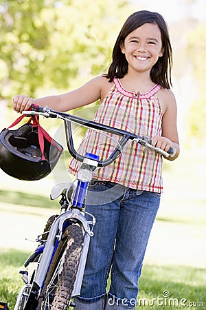 Young girl with bicycle outdoors smiling Stock Photo