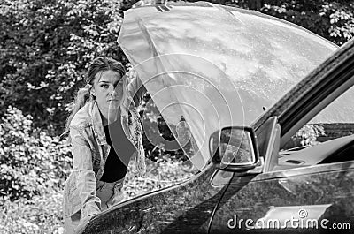 The young girl broke the car and she opened the hood and tried to repair the car on the road Stock Photo