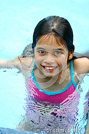A young girl with brown eyes enjoys being in the swimming pool Stock Photo