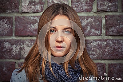 Young girl with brown straight hair next to brick wall Stock Photo