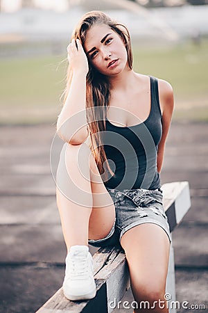 A young girl came to the stadium in the evening to train. The girl sat down to rest Stock Photo