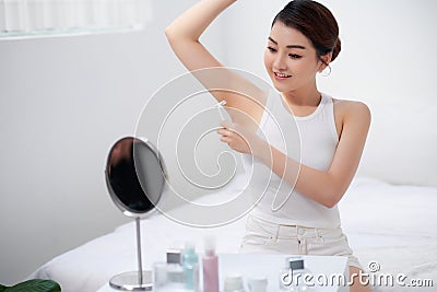 A young girl cares for her body, shaves her armpits with a white razor Stock Photo