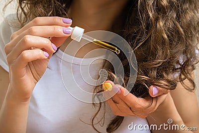 Young girl caring for curly hair tips with yellow oil Stock Photo