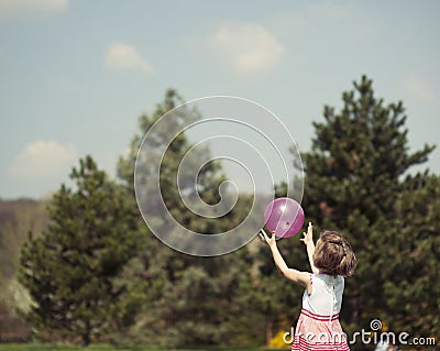 Young girl catching purple ball in park Stock Photo