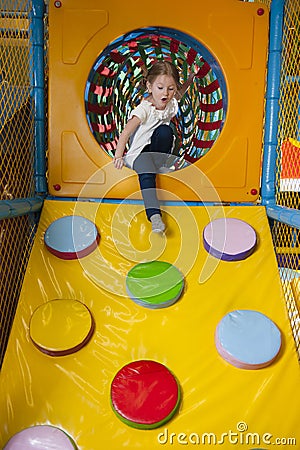 Young girl climbing down ramp in soft play centre Stock Photo