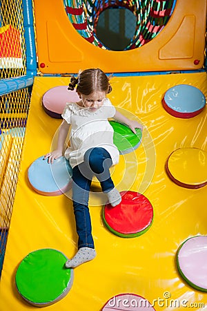 Young girl climbing down ramp in soft play centre Stock Photo