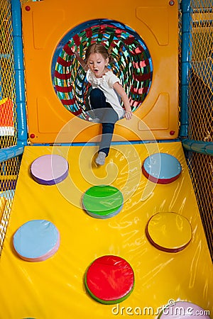 Young girl climbing down ramp in soft play centre Stock Photo