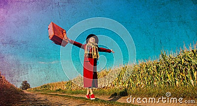 Girl coat with suitcase on a rural road near cornfield Stock Photo