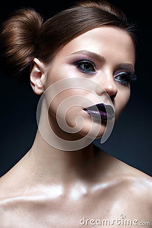 Young girl with creative makeup and hairdo. A beautiful model with bright eyes and purple lips. Shining skin. Stock Photo