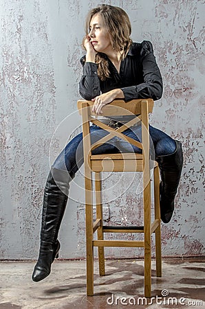 Young girl with curly hair in a black shirt, jeans and high boots cowboy western style Stock Photo