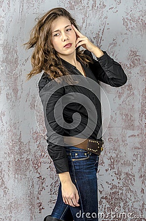 Young girl with curly hair in a black shirt, jeans and high boots cowboy western style Stock Photo