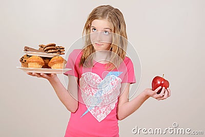 Young girl deciding junk food or apple Stock Photo